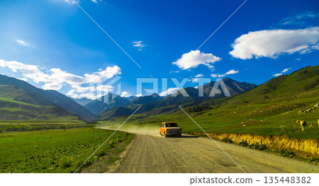 Car driving on dirt road with sheep in rural mountain landscape in Kyrgyzstan 135448382