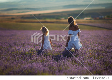 Woman girl lavender, walking through purple flower field at tranquil sunset Woman girl lavender, walking through purple flower field at tranquil sunset 135448525