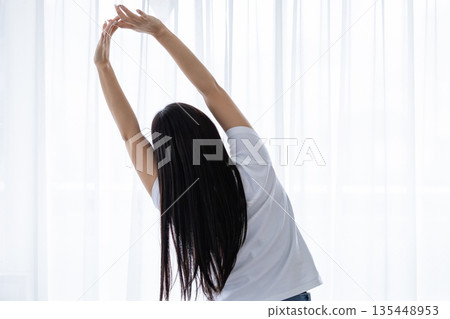 Young woman stretching by the window Young woman stretching by the window 135448953