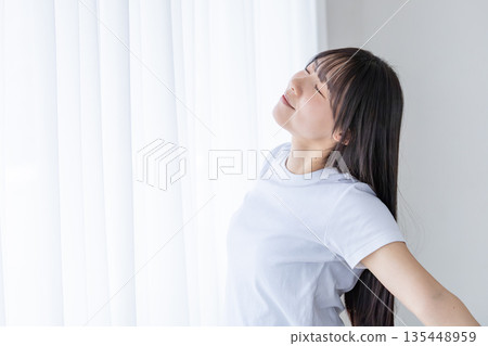 Young woman stretching by the window Young woman stretching by the window 135448959