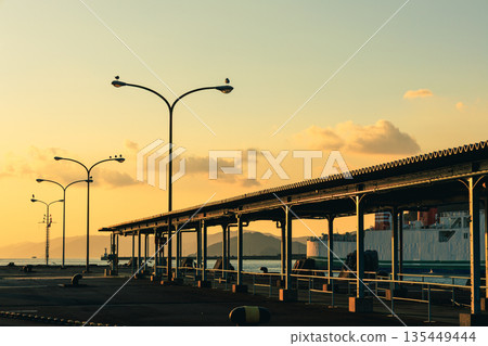 愛媛縣八幡濱市八幡濱港，黃昏時分，路燈閃爍，海面平靜，渡輪緩緩駛過。 135449444