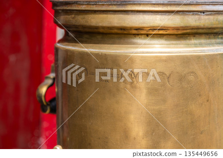Vintage brass tea urn with engravings and warm ambiance 135449656