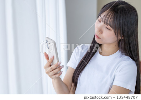 年輕女子拿著智慧型手機思考 135449707