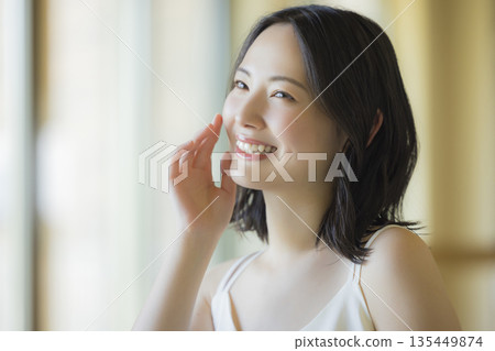 A woman looking in the mirror in the living room A woman looking in the mirror in the living room 135449874