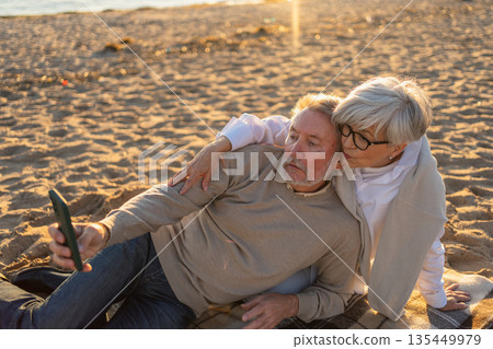 Video call. Senior couple making selfie having video call on beach outdoor. Mature old grandmother grandfather talking speaking online. Older generation modern tech usage. Virtual meeting online chat Video call. Senior couple making selfie having video call on beach outdoor. Mature old grandmother grandfather talking speaking online. Older generation modern tech usage. Virtual meeting online chat 135449979