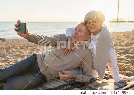 Video call. Senior couple making selfie having video call on beach outdoor. Mature old grandmother grandfather talking speaking online. Older generation modern tech usage. Virtual meeting online chat Video call. Senior couple making selfie having video call on beach outdoor. Mature old grandmother grandfather talking speaking online. Older generation modern tech usage. Virtual meeting online chat 135449981