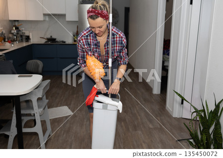 Woman Prepares Cleaning Supplies in the Kitchen of Her Apartment Woman Prepares Cleaning Supplies in the Kitchen of Her Apartment 135450072