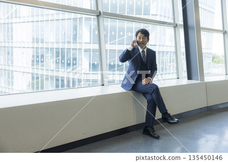 A middle-aged businessman who makes a phone call with a smartphone 135450146