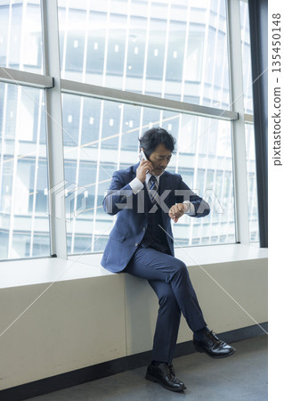 A middle-aged businessman who makes a phone call with a smartphone A middle-aged businessman who makes a phone call with a smartphone 135450148