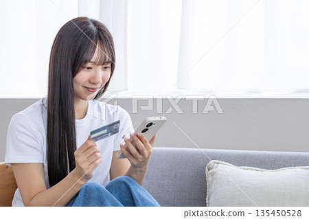 Young woman with smartphone and credit card 135450528