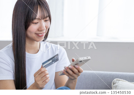 年輕女子手持智慧型手機和信用卡 135450530