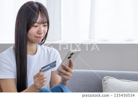 年輕女子手持智慧型手機和信用卡 135450534