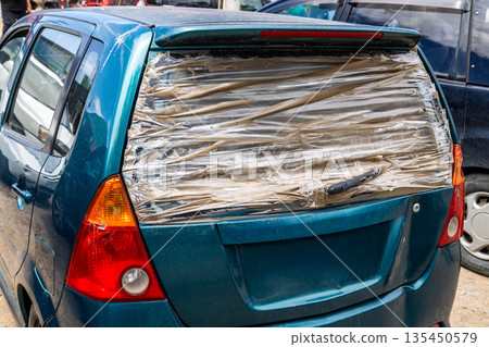 Car with broken rear window covered with clear tape Car with broken rear window covered with clear tape 135450579
