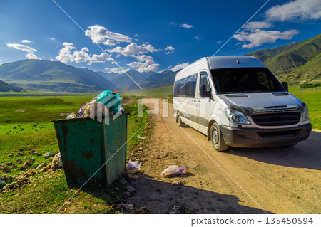 Trash bin overflowing with garbage bags in rural mountain setting Trash bin overflowing with garbage bags in rural mountain setting 135450594