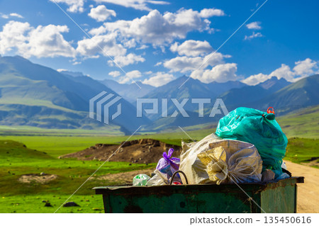 Rusty green trash bin filled with colorful garbage bags outdoors Rusty green trash bin filled with colorful garbage bags outdoors 135450616