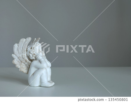 White ceramic angel figurine on white background for design. Faith, symbols, and traditions. 135450801