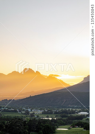 Sunset over mountain landscape with village in valley. Golden hour light Sunset over mountain landscape with village in valley. Golden hour light 135450843