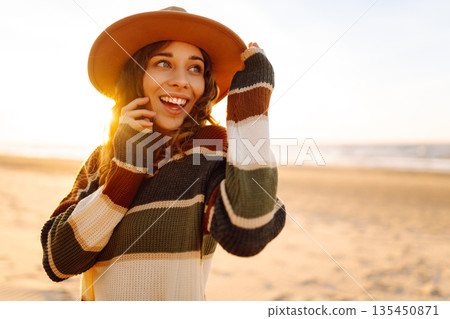 Beautiful curly woman on beach in cold sunny weather, deeply breathing fresh ocean breeze. Lifestyle Beautiful curly woman on beach in cold sunny weather, deeply breathing fresh ocean breeze. Lifestyle 135450871