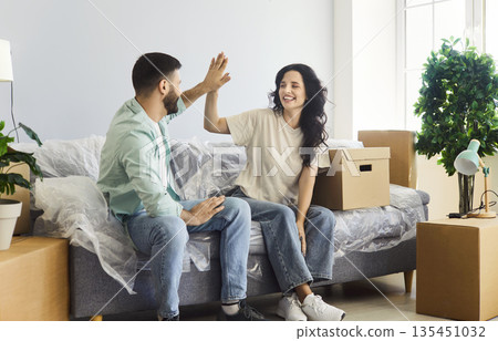 Happy couple moving into new home apartment, young people give high five 135451032