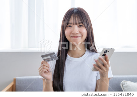 年輕女子手持智慧型手機和信用卡 年輕女子手持智慧型手機和信用卡 135451040