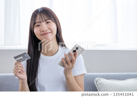 Young woman with smartphone and credit card 135451041