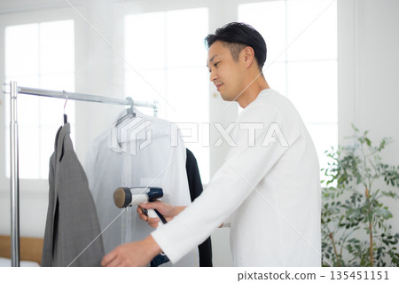 Man using a steamer on clothes 135451151
