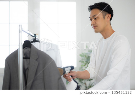 Man using a steamer on clothes 135451152