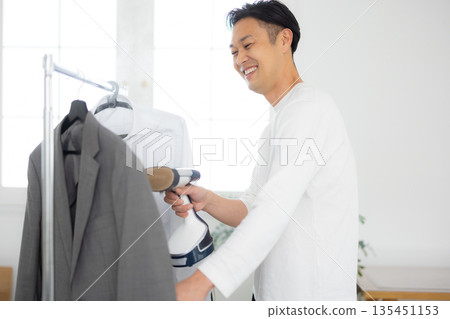 Man using a steamer on clothes Man using a steamer on clothes 135451153