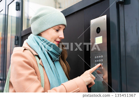 Woman calling the intercom Woman calling the intercom 135451367