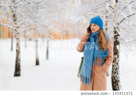 Woman in a coat talking on the phone Woman in a coat talking on the phone 135451371