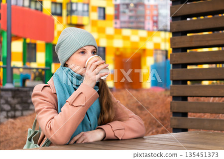 A woman sits in the courtyard of a house and drinks coffee A woman sits in the courtyard of a house and drinks coffee 135451373