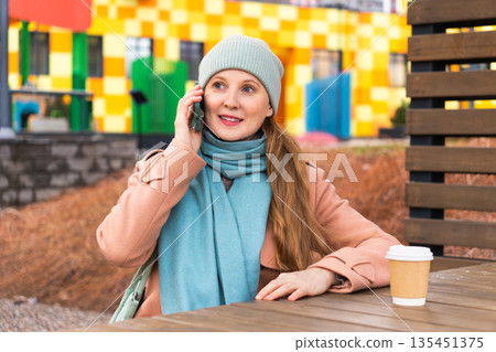 A woman on the street talking on the phone 135451375