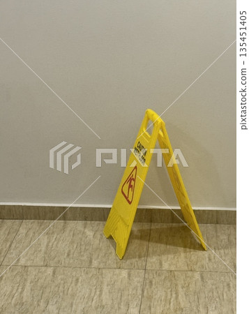 Wet floor sign on tile floor indoors, a concept of safety and caution in public spaces 135451405