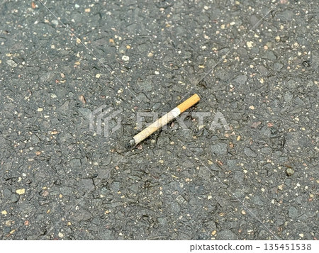 Cigarette Butt On Rough Asphalt, CloseUp, Discarded Filter With Smoldering Ash, Granular Pavement Texture With Small Stones, Faded Paint Specks, Urban Parking Lot Atmosphere, Littering Cigarette Butt On Rough Asphalt, CloseUp, Discarded Filter With Smoldering Ash, Granular Pavement Texture With Small Stones, Faded Paint Specks, Urban Parking Lot Atmosphere, Littering 135451538