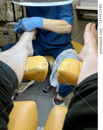 Hardware medical pedicure using a drill and nail files. A patient has a pedicure at a podiatrist. A dangerous fungal lesion of human toenails. Onychomycosis, treatment of nail fungus. Hardware medical pedicure using a drill and nail files. A patient has a pedicure at a podiatrist. A dangerous fungal lesion of human toenails. Onychomycosis, treatment of nail fungus. 135451540