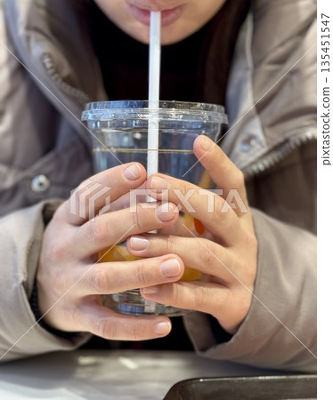 Hands Holding Iced Coffee Cup CloseUp, Student Gripping Cold Beverage With Both Hands At Cafe Table, Straw Near Lips, Condensation Beading On Plastic Cup, Casual Winter Jacket, Smartphone Hands Holding Iced Coffee Cup CloseUp, Student Gripping Cold Beverage With Both Hands At Cafe Table, Straw Near Lips, Condensation Beading On Plastic Cup, Casual Winter Jacket, Smartphone 135451547