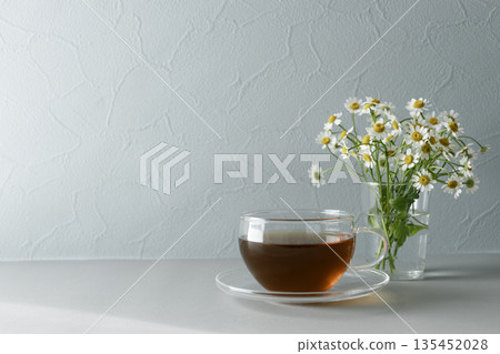 Glass teacup and matricaria: Tea time with space Glass teacup and matricaria: Tea time with space 135452028
