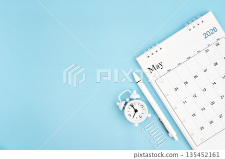 May 2026, Monthly desk calendar for 2026 year and alarm clock with paper clips on blue color background. May 2026, Monthly desk calendar for 2026 year and alarm clock with paper clips on blue color background. 135452161