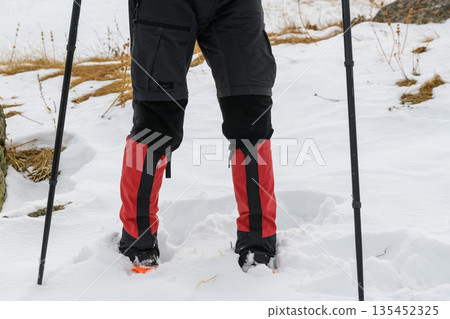 Hiker legs with crampons in snow 135452325