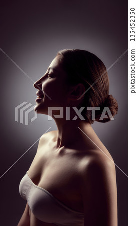 Artistic low light portrait of woman with soft shadows and neutral background. Artistic low light portrait of woman with soft shadows and neutral background. 135452350
