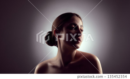 Low key female portrait with upward gaze and soft highlights. Low key female portrait with upward gaze and soft highlights. 135452354
