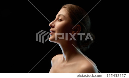 Low key female profile portrait with soft rim lighting. Low key female profile portrait with soft rim lighting. 135452357