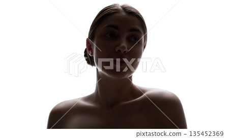 Low light female portrait with soft shadows and calm expression. 135452369