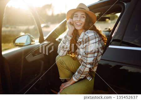 Joyful traveler embraces nature at sunset by lakeside with open car door, freedom, adventure. Joyful traveler embraces nature at sunset by lakeside with open car door, freedom, adventure. 135452637