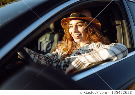 Beautiful young woman driving her car. Woman traveler. Summer vacation and adventure. 135452638