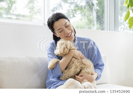 A woman in her 50s holding her pet dog (a 10-month-old female Bichon Poo) 135452690