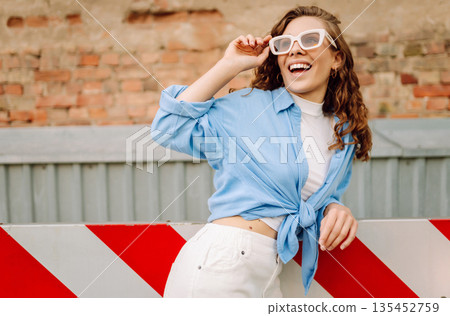 Fashionable young woman in good mood posing outdoors. Sunny day. Concept of lifestyle, fashion 135452759