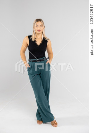 Businesswoman posing with hands in pockets in studio setting Businesswoman posing with hands in pockets in studio setting 135452917