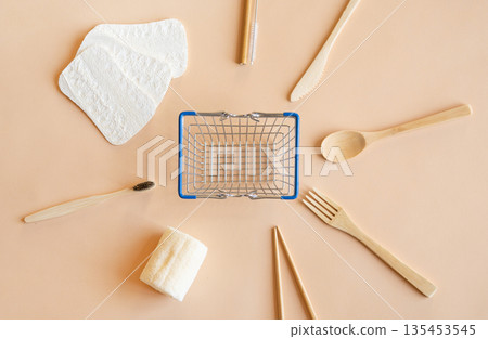 Shopping concept. Ecological goods: cutlery, toothbrush, sponge for washing and dishes in a composition with a shopping basket on a beige background. Flat lay 135453545