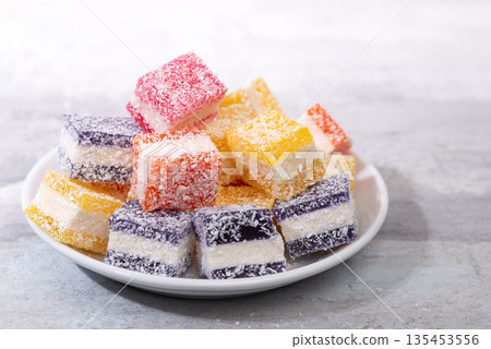 Cubes of multi-colored marmalade in powdered sugar on plate. The concept of baby sweets. Cubes of multi-colored marmalade in powdered sugar on plate. The concept of baby sweets. 135453556